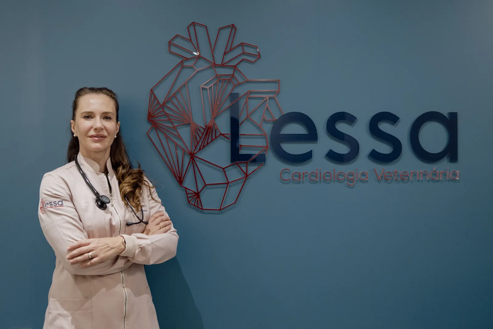 Veterinária da Lessa diante da parede com o logo da clínica